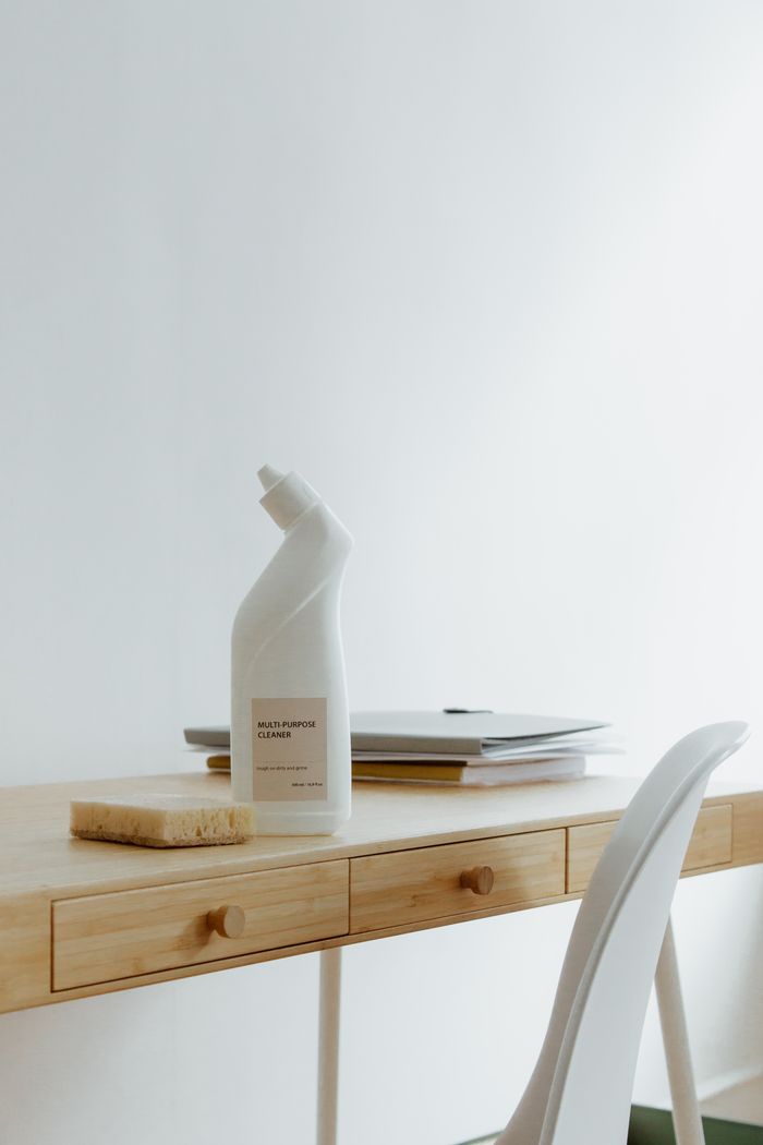 Un bureau de télétravail propre et bien rangé, avec un flacon de produit nettoyant et une éponge, mettant en avant la simplicité et l’aspect fonctionnel.